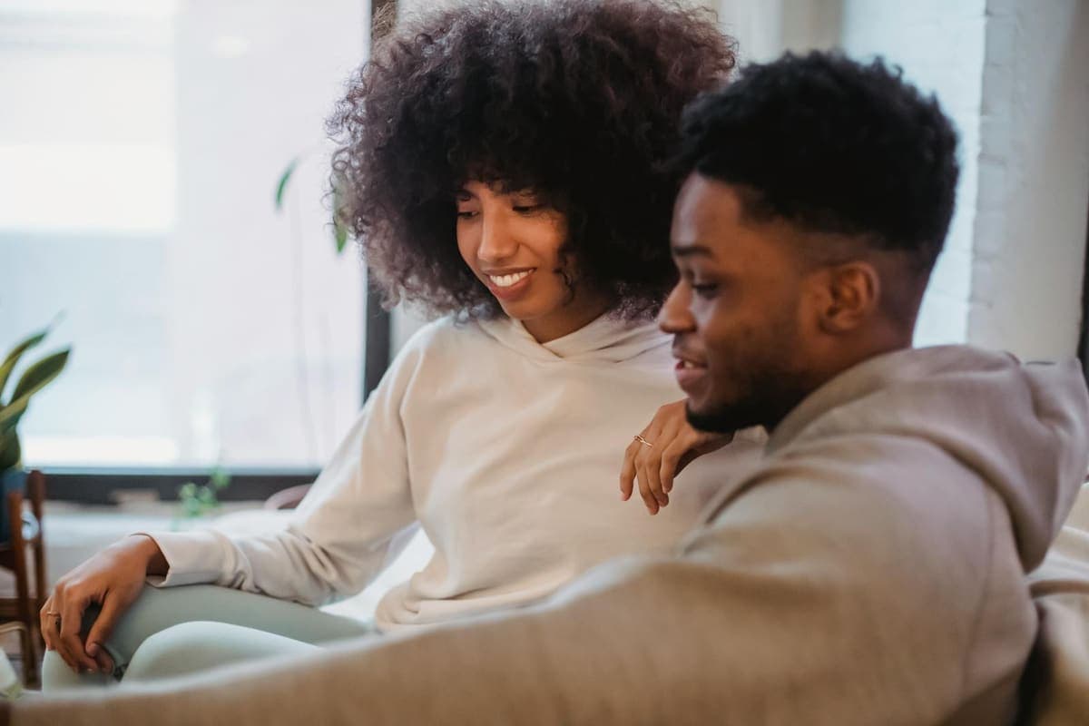 Couple relaxing together at home on a sofa in soft daylight.
