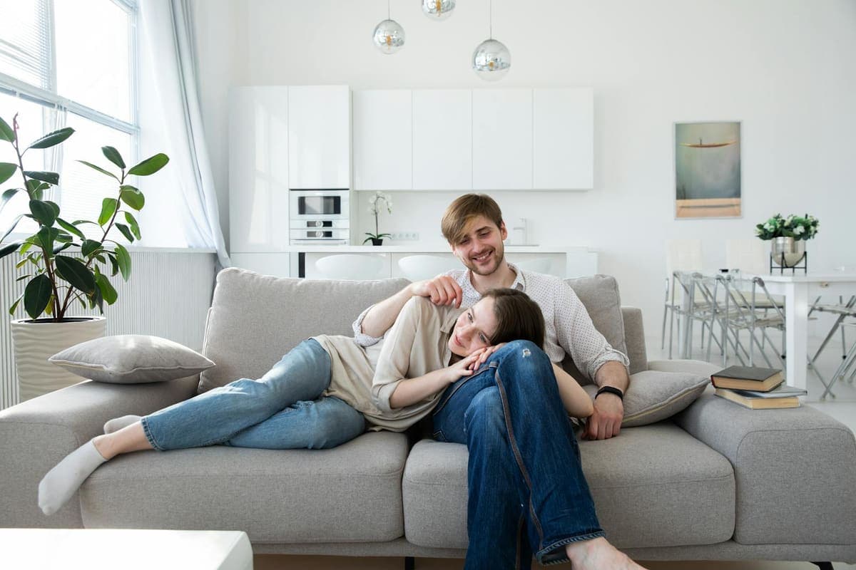 Smiling couple sitting close together on a couch at home.
