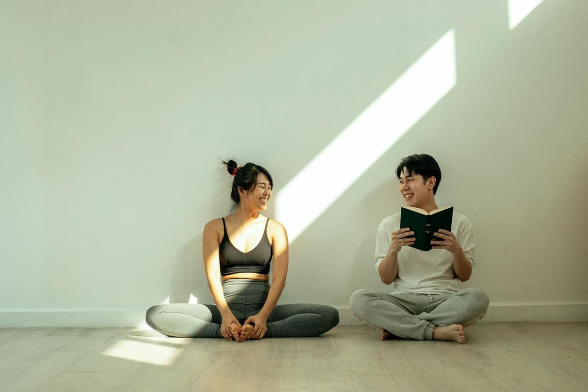 Couple sitting together on the floor at home and smiling at each other.