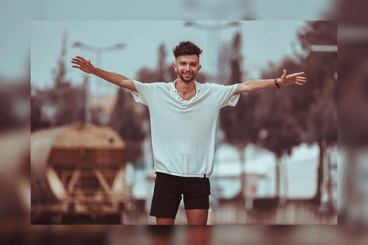 Smiling man standing outside in casual clothing.