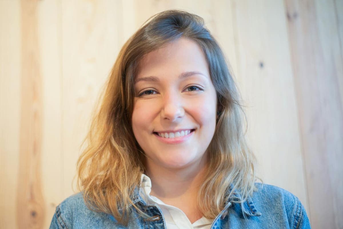 Smiling woman in a denim jacket with her face fully visible.